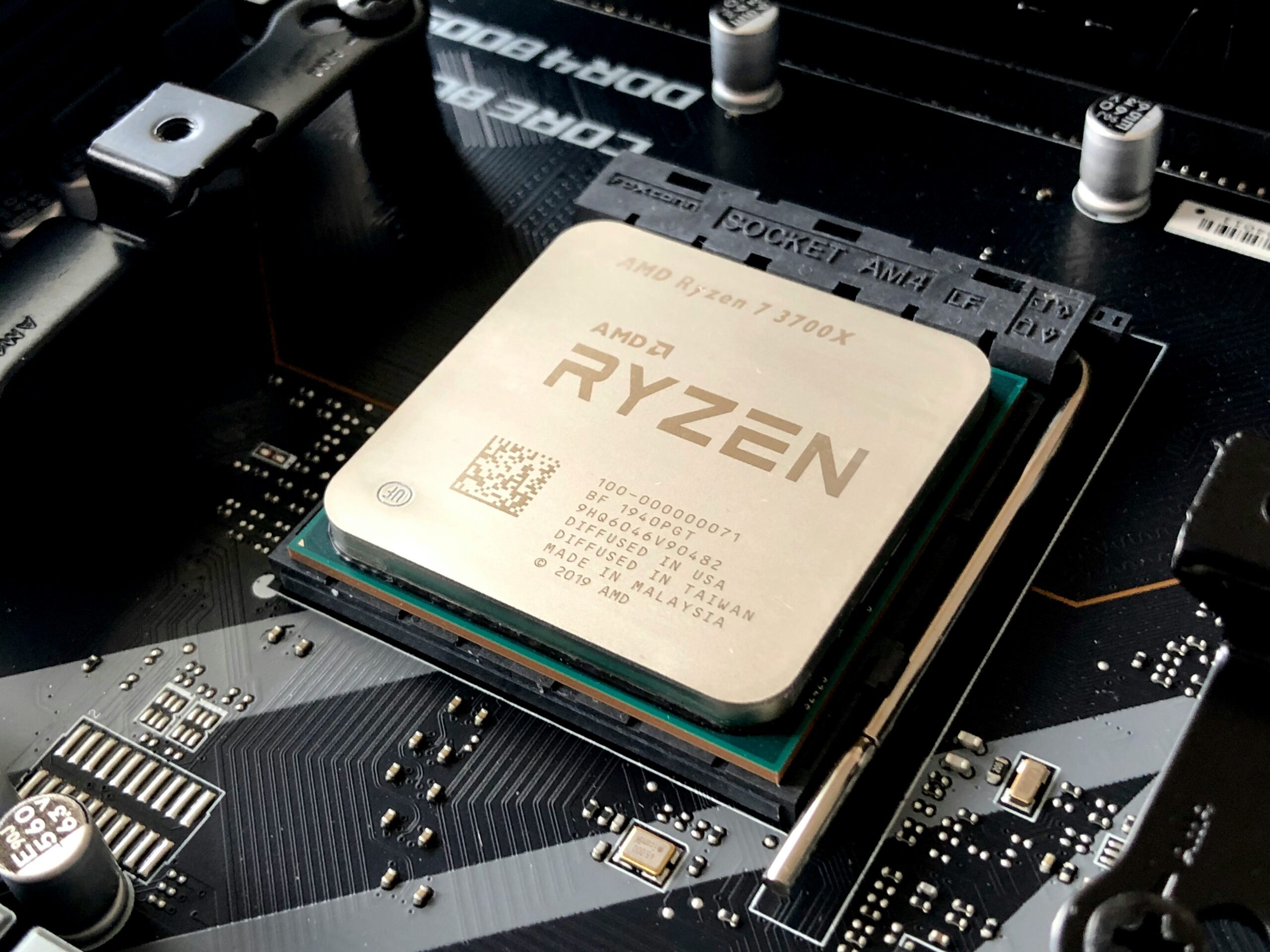 Close-up of an AMD Ryzen 7 3700X CPU chip on a black motherboard